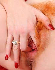 Naughty milf Sasha Brand strips off her clothes and fondles her red haired Anilos pussy on the sofa